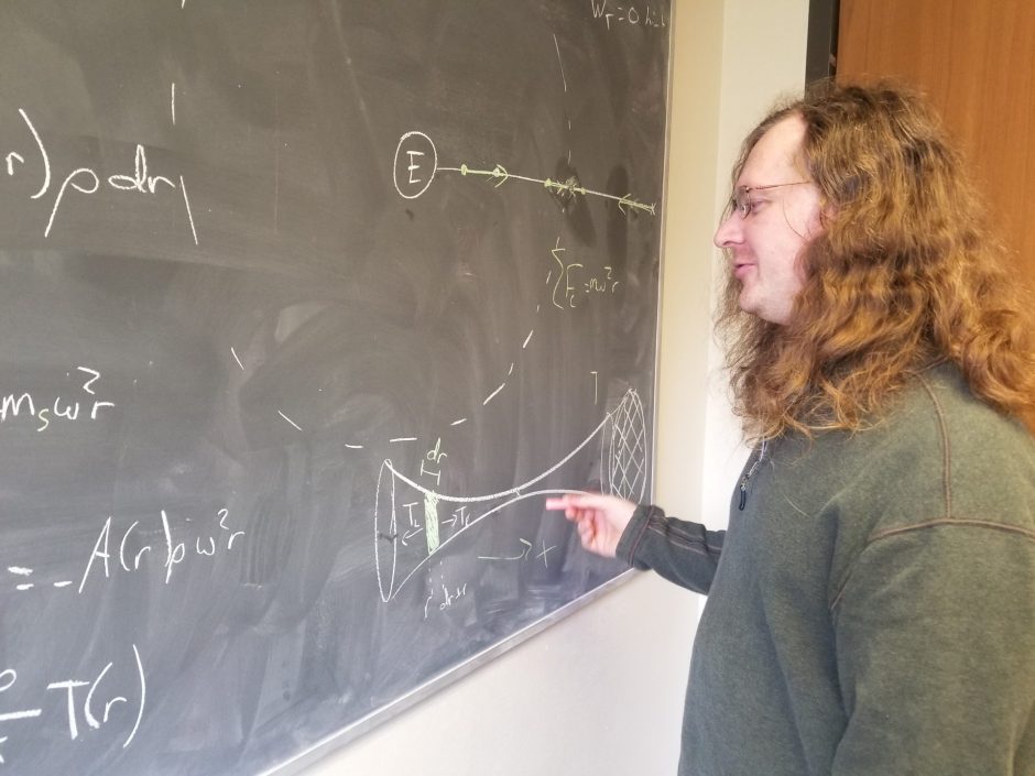 SU Professor Walter Freeman working on an equation on the chalkboard. Freeman teaches multiple astronomy classes at Syracuse and said he talked about black hole heavily in class on Thursday
