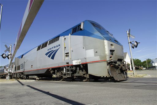 An Amtrak commuter train moves through a crossing gate.