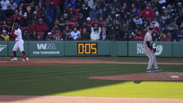 Baltimore Orioles relief pitcher Logan Gillaspie, right, starts to deliver a pitch to Boston Red Sox's Connor Wong, as the pitch clock ticks to five seconds, during the eighth inning of an opening day baseball game at Fenway Park, Thursday, March 30, 2023, in Boston.