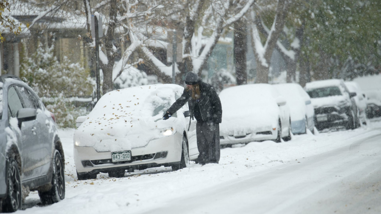 A motorist clears snow from a vehicle after a winter storm dumped up to a foot of snow in some Front Range communities on Sunday, Oct. 29, 2023, in Denver.