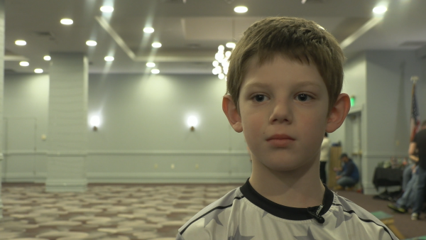 Eight-year-old Ashton Pendolf stands in front of the cornhole boards and shares his experience from this weekend's tournament.