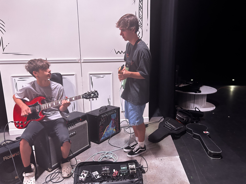 Brad Allyn, 17, assisting a younger camper that also plays guitar.