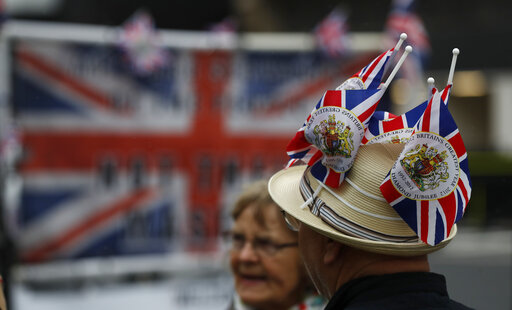 A man wearing a colorful hat is demonstrating in front of the British Parliament in favor of Brexit.