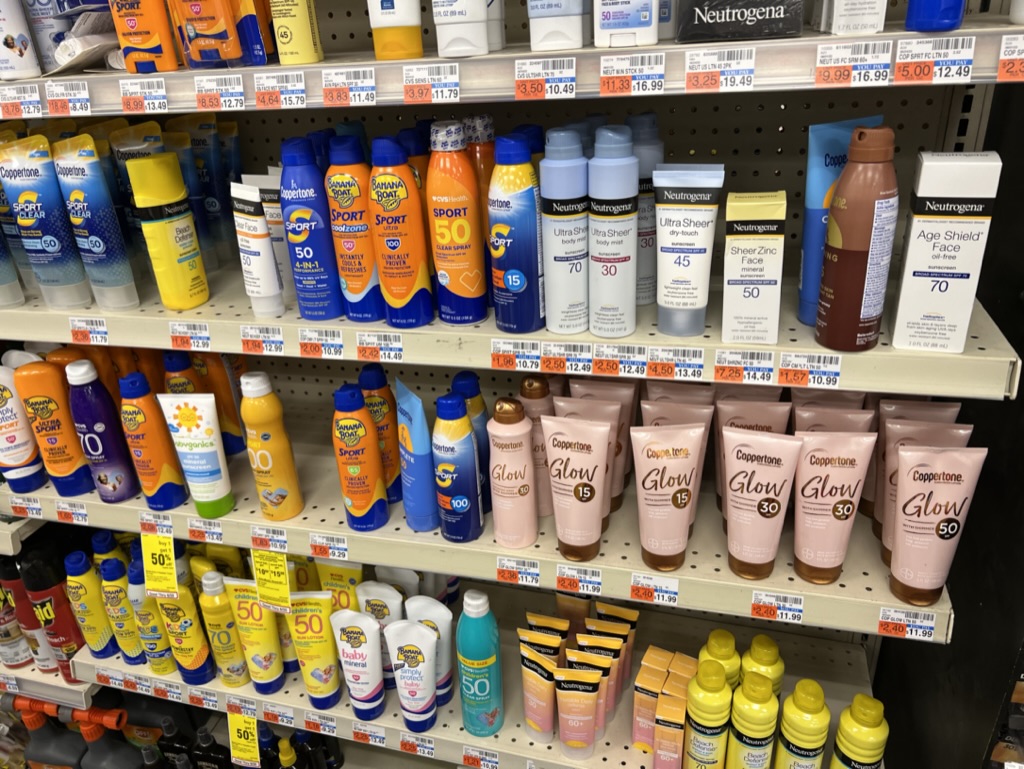 Sunscreen bottles line the shelves of a pharmacy.