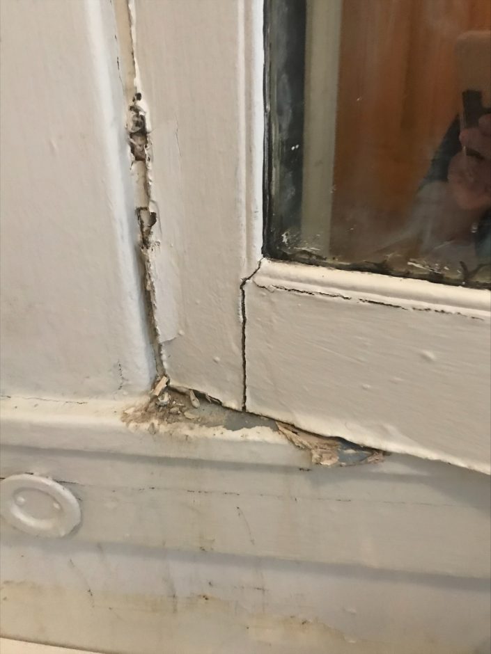 A close-up of a window with chipped paint, exposing lead paint dust on the window sill