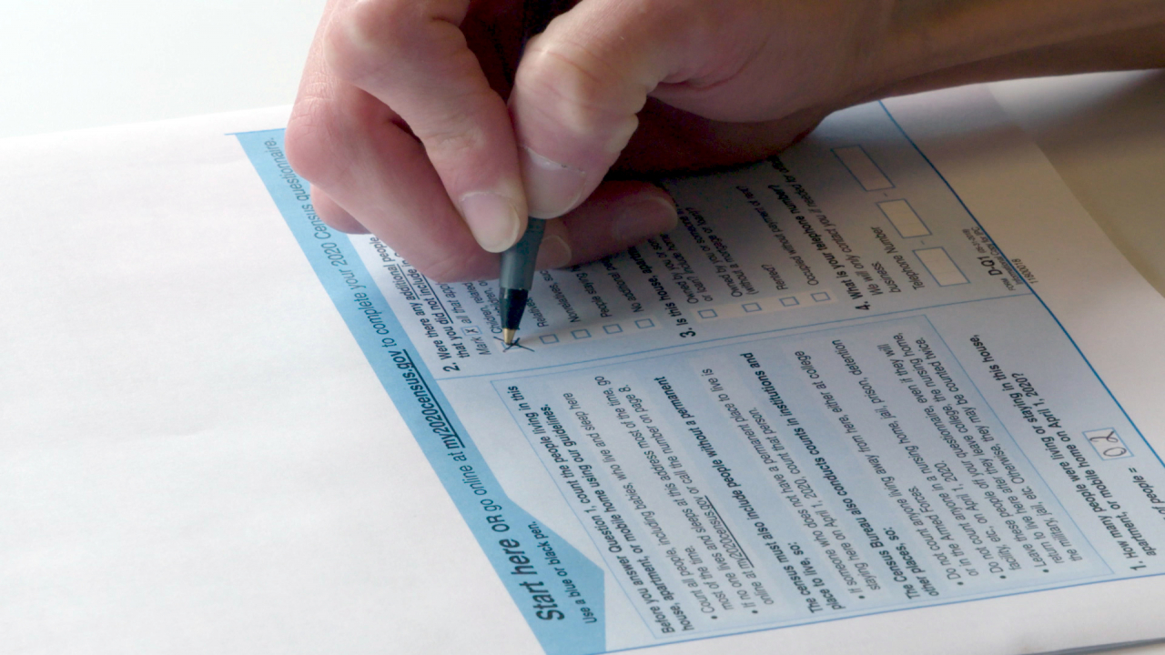 A hand filling out the census response ballot.
