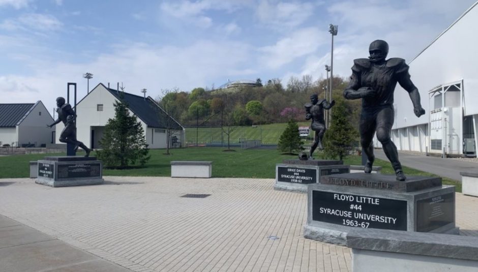 A photo of statues of Jim Brown, Ernie Davis, and Floyd Little