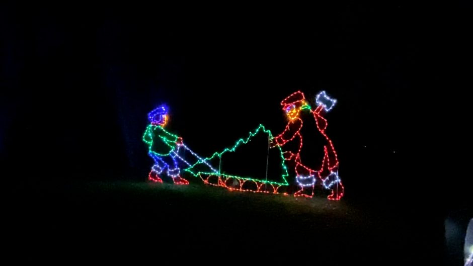 Christmas lights of two people cutting down a Christmas tree
