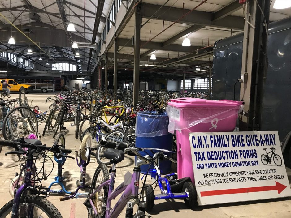 a CNY Family Bike Giveaway Sign next to a stack of bikes