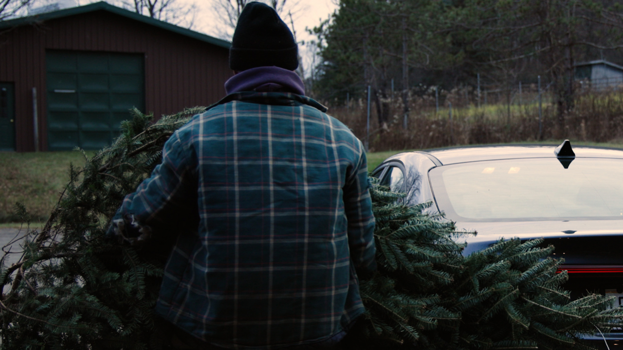 “Dan Martini, owner of Syracuse Christmas Tree Farms, loads a Christmas tree onto a customer’s car. NCC News photo by Brendan Custer.”