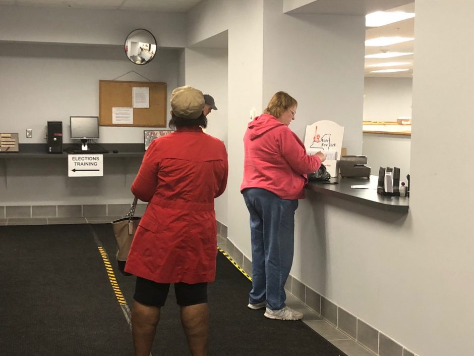 People line up at the counter of the Onondaga County Board of Elections