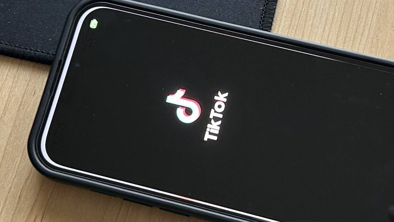 Phone loading in to TikTok with logo displayed at forefront.
