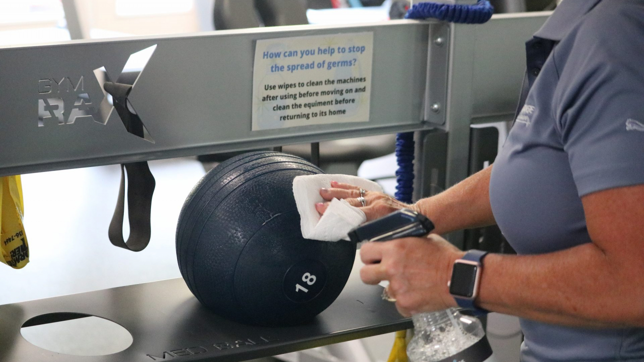 Advantage Fitness employee wiping down weighted ball.