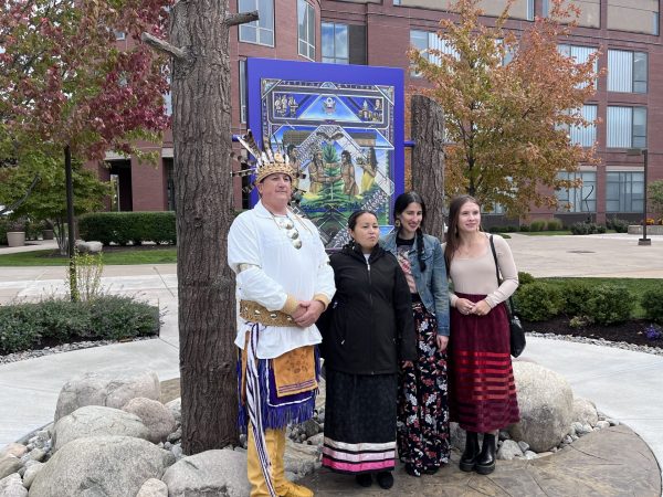 Members of the Haudenosaunee stand with a new piece of artwork on Indigenous People's Day at Syracuse University.