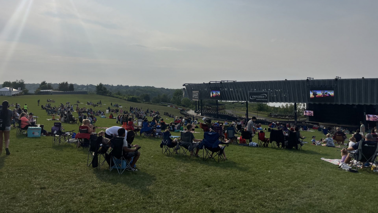 People sitting on the lawn of Empower Amphitheatre.