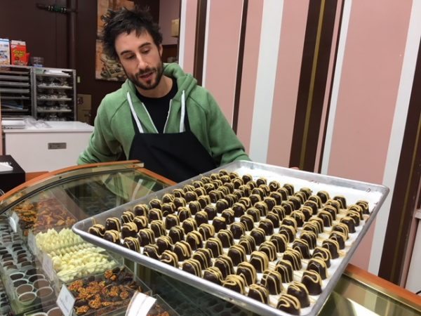 The owner of Sweet On Chocolate presents butterscotch truffles on a tray.