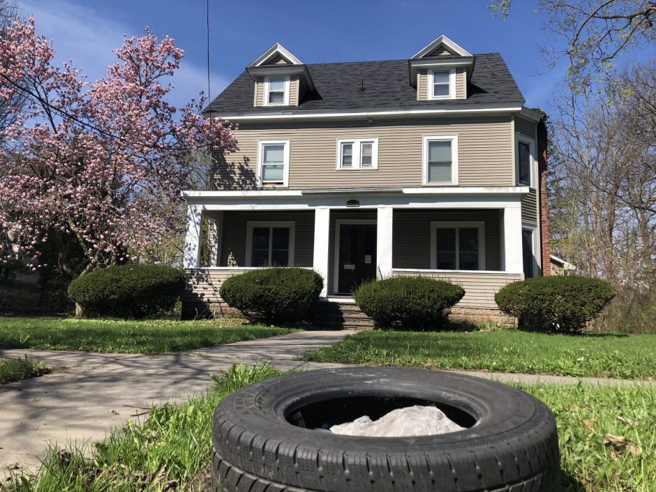 Street view of house with a tire outside on the sidewalk.