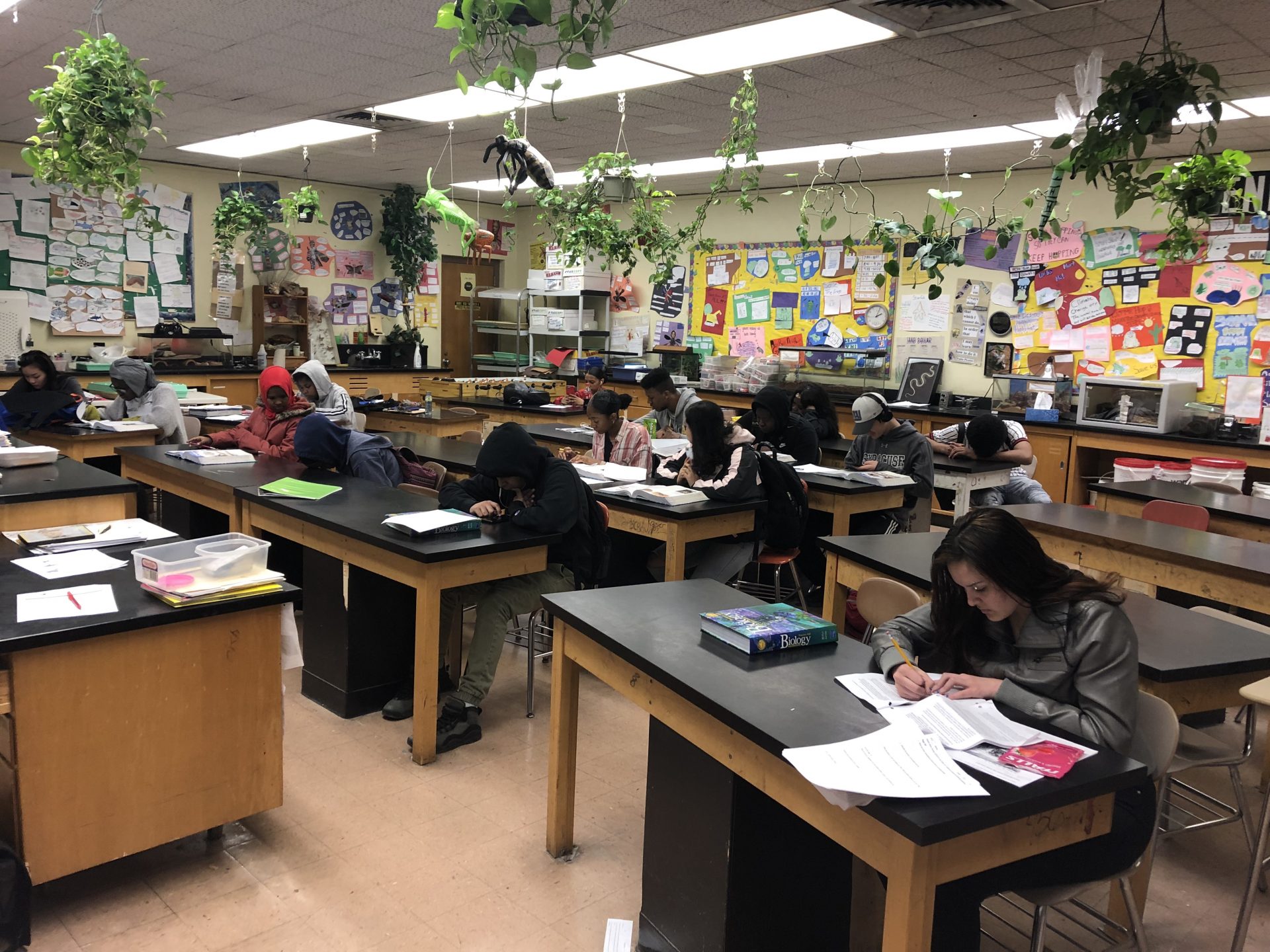Syracuse high school students sitting at desks in the classroom with their heads down working in their biology books.