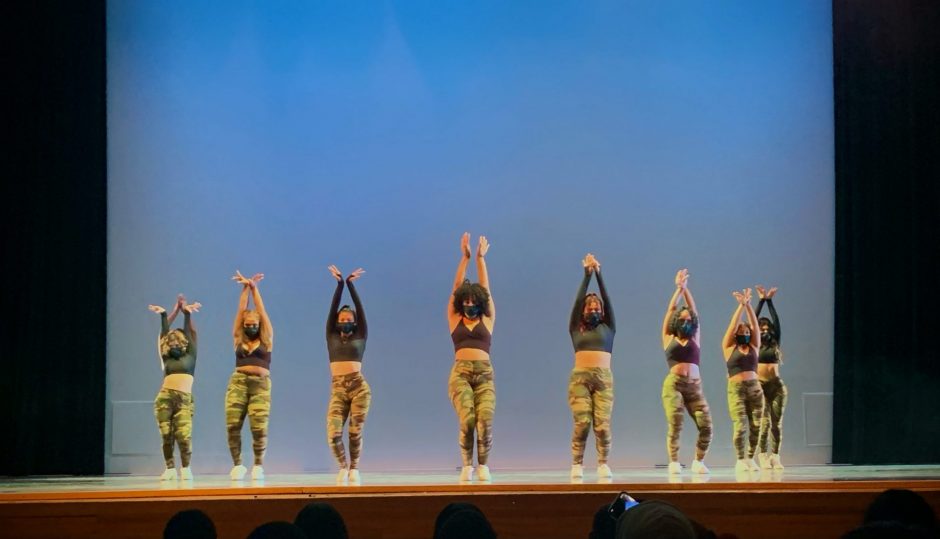 The Raices girls all lined up wearing matching black tops and camo print leggings mid-dance.