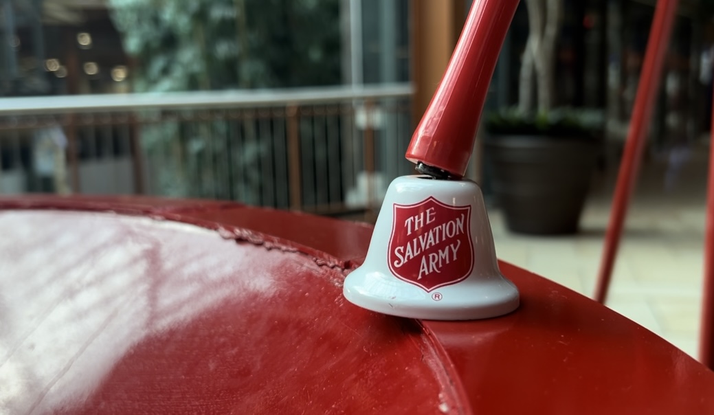 A Salvation Army bell sitting on the donation kettle.