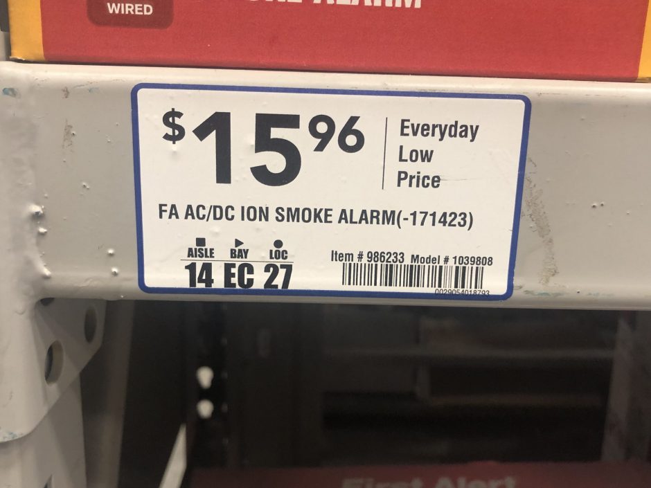 A price sticker for a smoke detector on a shelf.