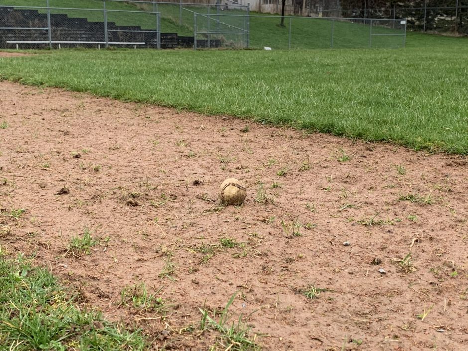 An old dirty baseball sits on the weed-filled infield of Fowler High School's current baseball field.