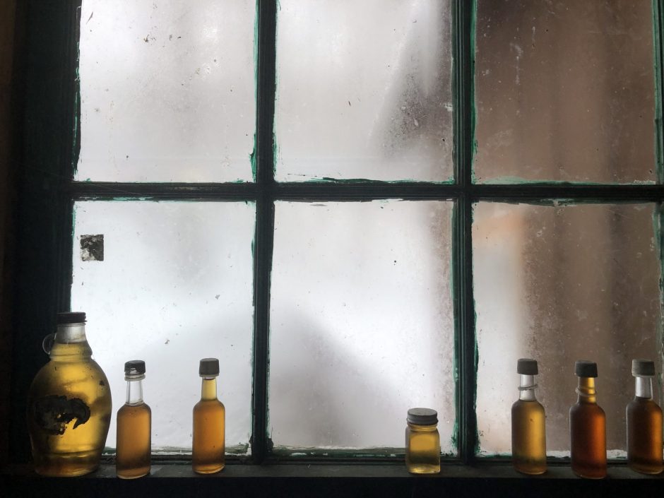 Bottles of syrup sitting on a window.