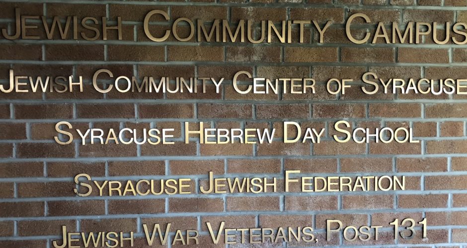 A brick wall in the Jewish Community Center where it lists the different services and amenities offered there.