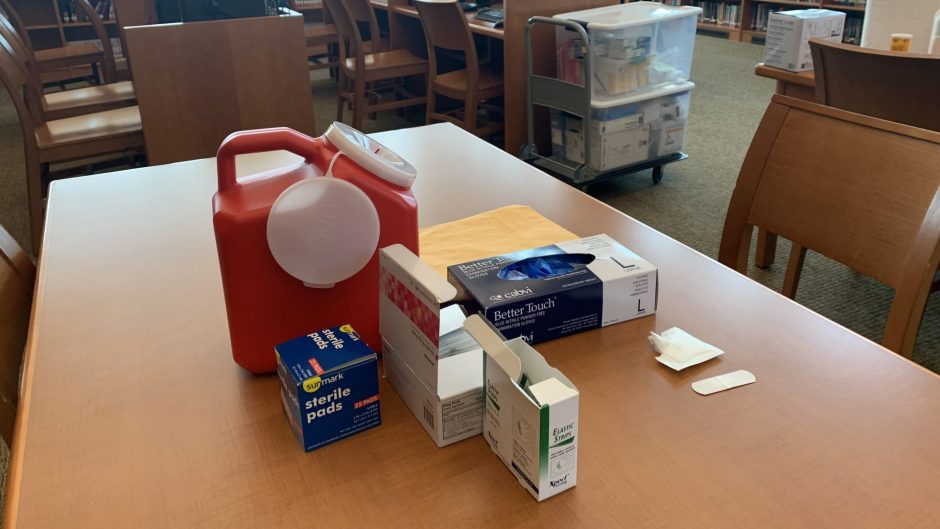A table with gloves, sterile pads and a sharps container.