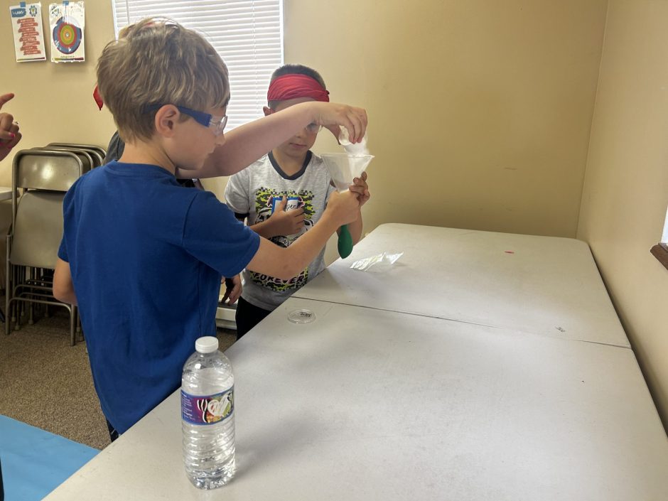 Campers conducting a chemical reaction with vinegar and baking soda.