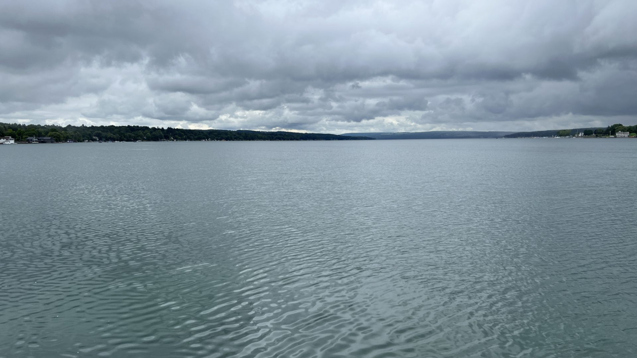 View of Skaneateles Lake from the north side at end of pier on an overcast day with calm water.
