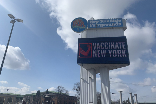 Image of billboard outside of the NYS Fairgrounds with a photo that says "Vaccinate New York" on the screen.