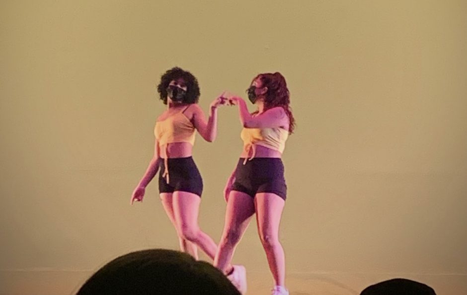 The two co-chairs grab hands together on stage at the end of a dance number.