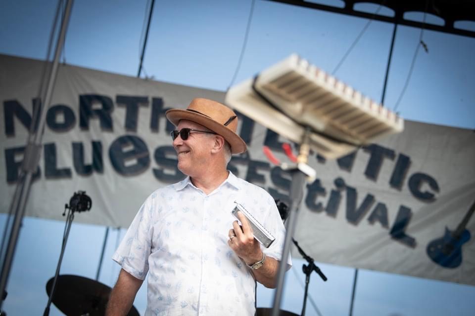 Mark Hummel performing with a harmonica at a festival.