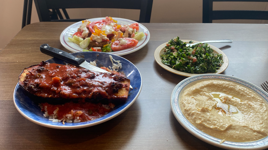 Lebanese cuisine on the table is falafel salad (top left), tabbouleh (top right), hummus (bottom right), and an eggplant dish with rice (bottom left)