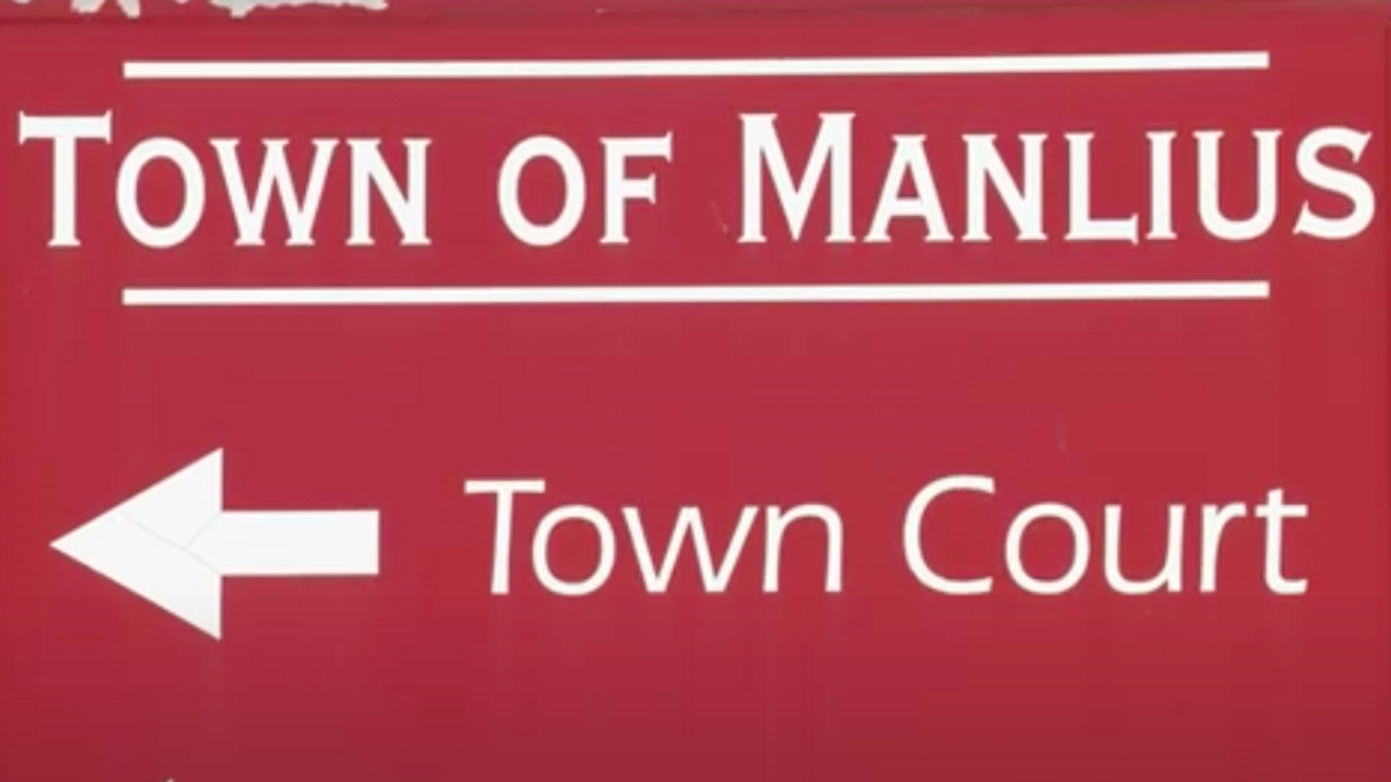 A sign with the Town of Manlius Town Court arrow pointing to the left