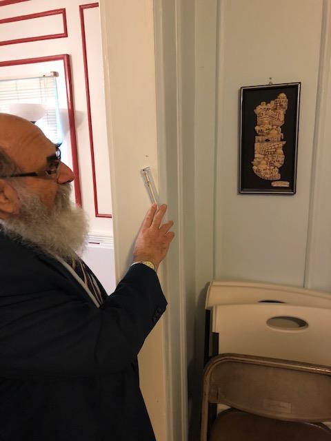 Rabbi Yakov Rapoport touches the Mezulah hung by his door.
