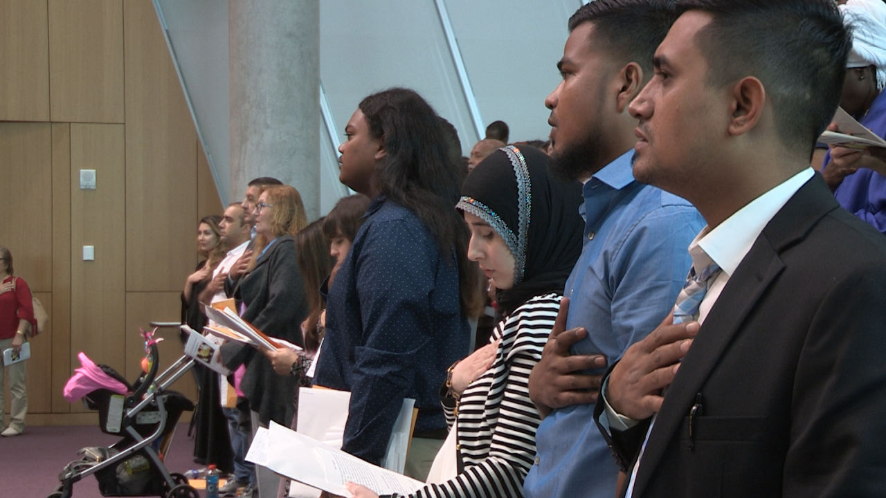 New citizens hold their hands over their hearts.
