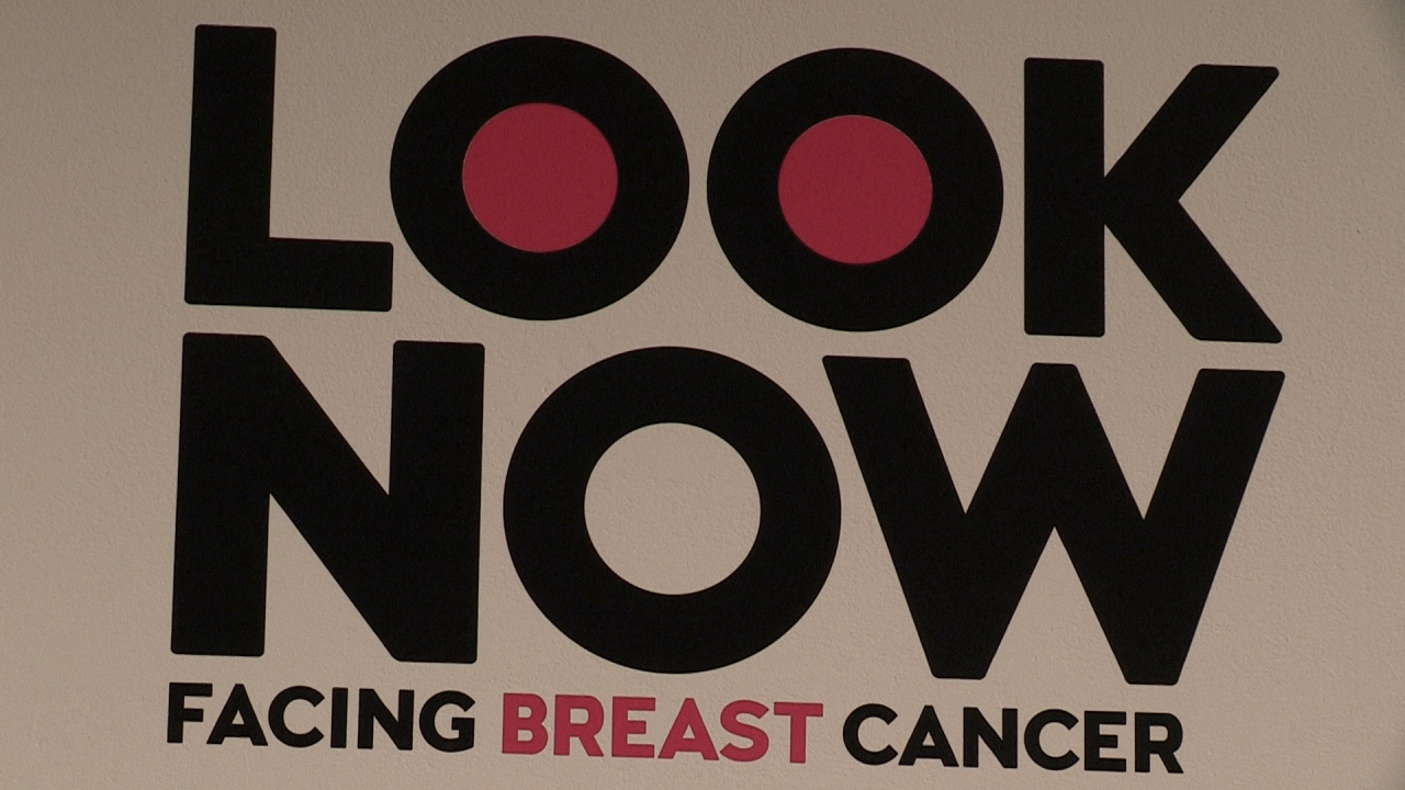 A sign that says Look Now: Facing Breast Cancer