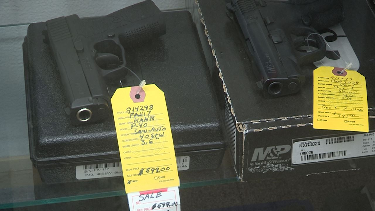 Two black handguns on top of cases with yellow price tags