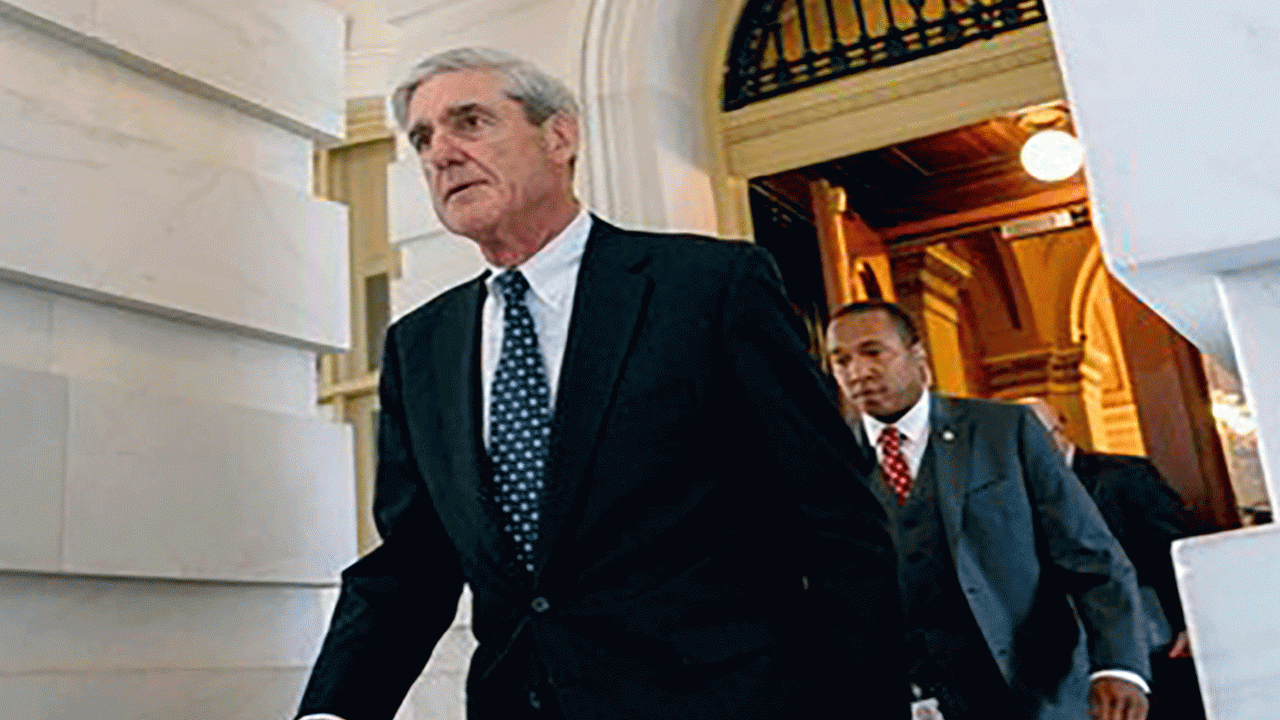 Robert Mueller is leaving a building with several people following behind him.