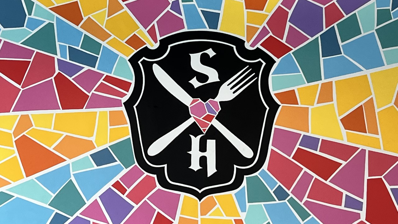 A vibrant painting surrounding the Strong Hearts Cafe logo is placed on the left wall inside the shop.