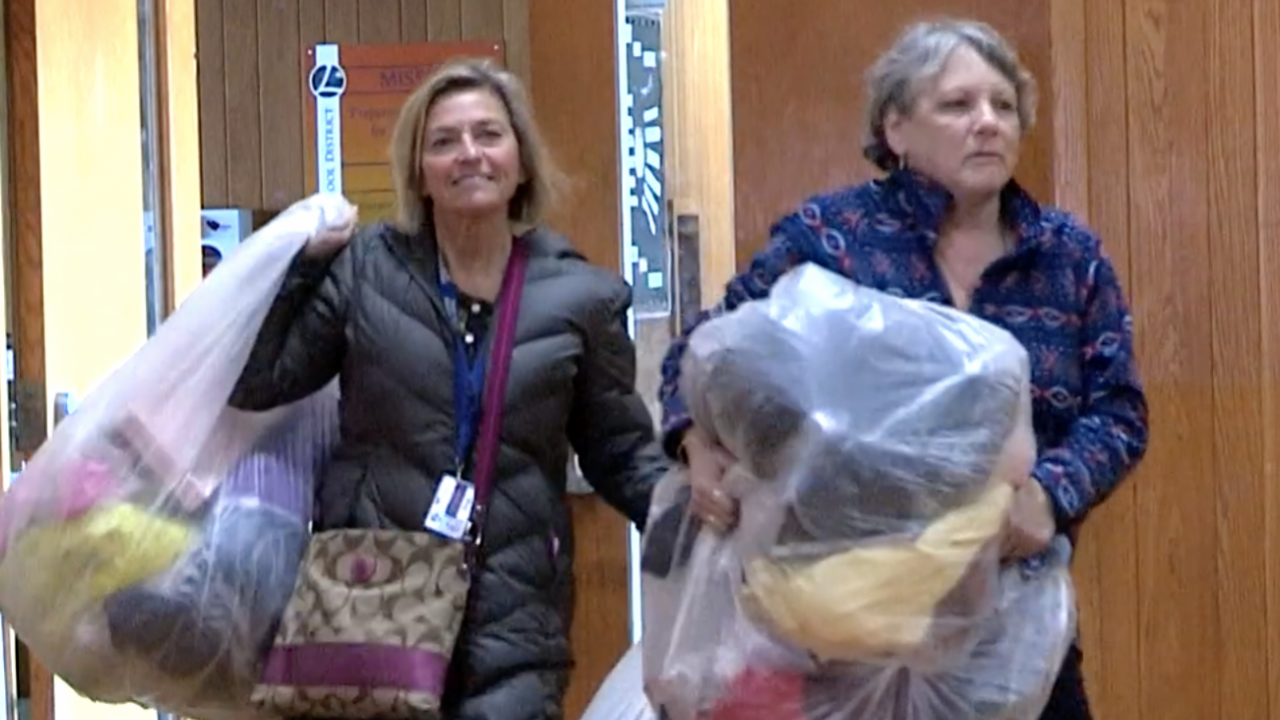Anne Oliver and Jeanne Cronise carrying bags of donated dresses