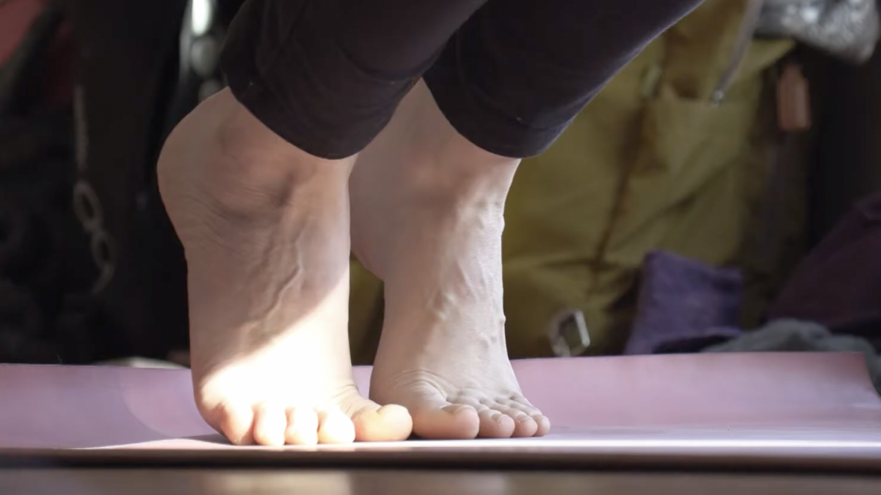 There are feet on a yoga mat.