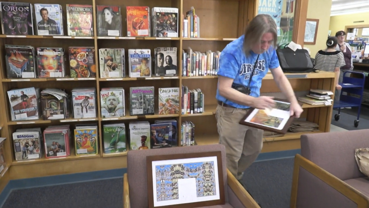 Artist William Hall sets up one of his photographs at Petit Branch Library