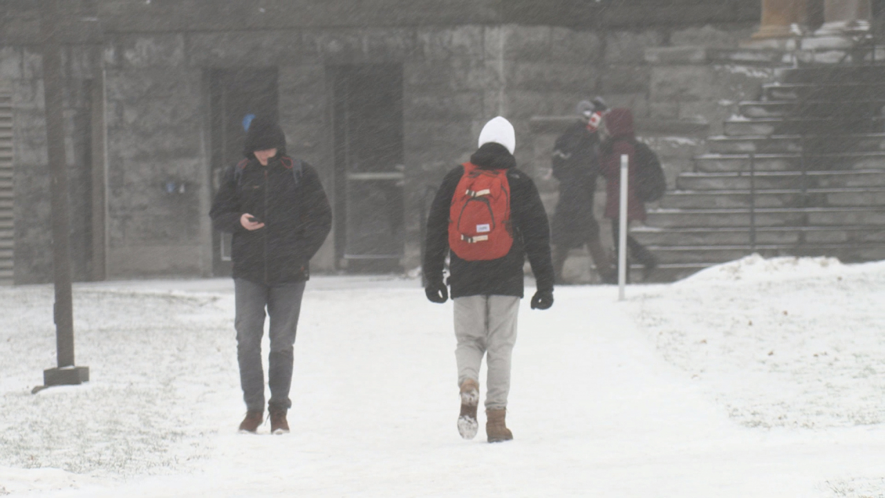Two men walk in opposite directions on a snowy path.