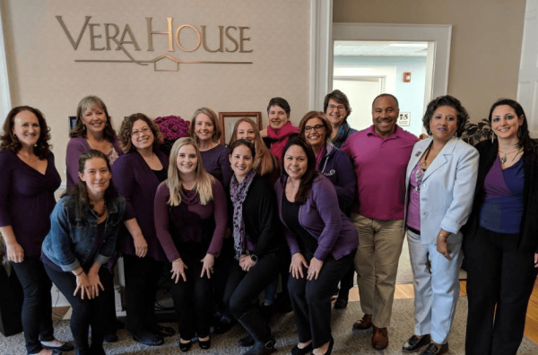 Staff members at Vera House, dressed in purple, pose for a group photo.