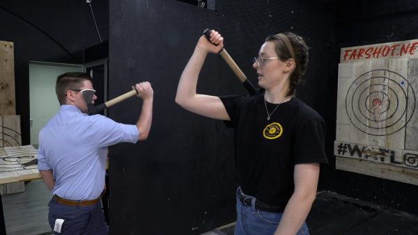 Reporter Michael O'Connor and axe throwing coach Evelyn Oliver work on throwing form with tomahawks