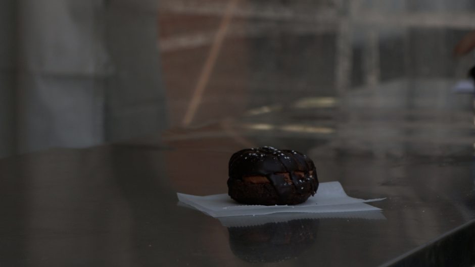 A customer is handed a chocolate donut at the Glazed and Confused donut shop stand