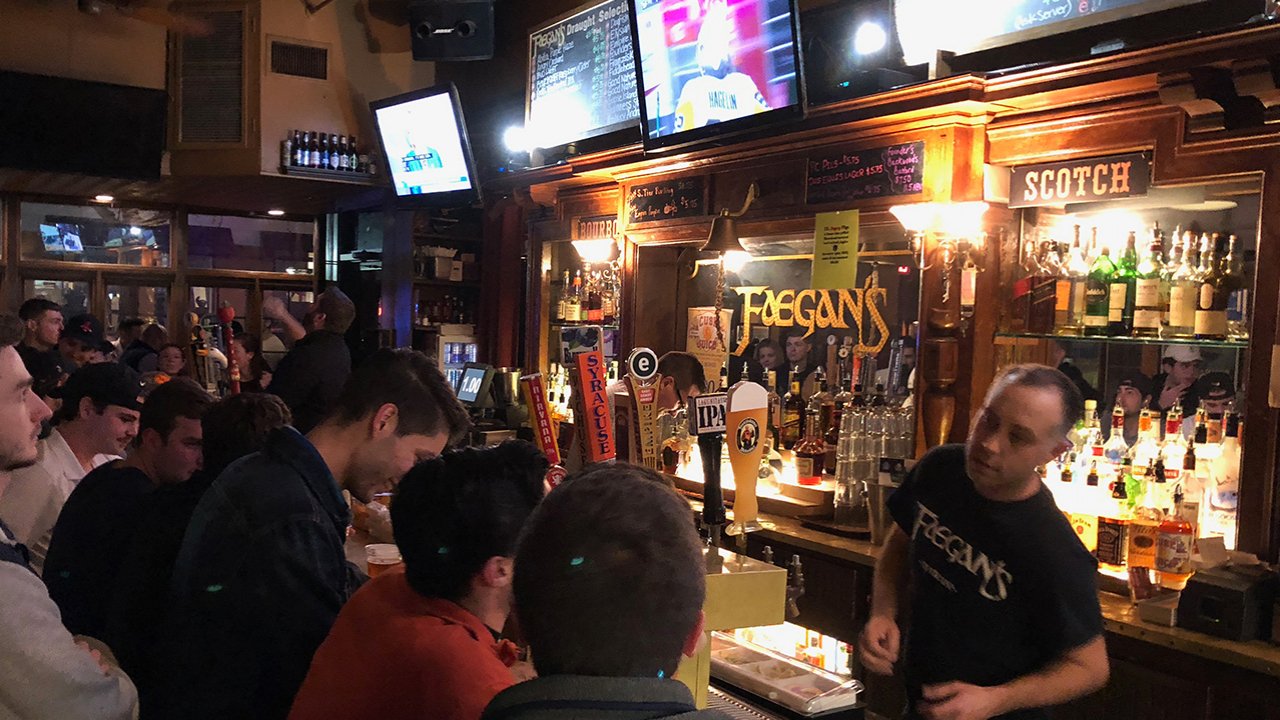 Bartender serves customers inside of Faegan's Cafe & Pub